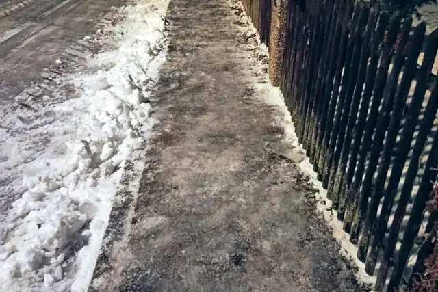 Geräumter Gehweg entlang eines Zauns