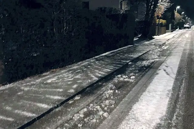 Geräumter Gehweg an einer Straße bei Nacht