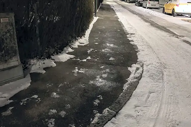 Geräumter Gehweg bei Nacht nach Schneefall